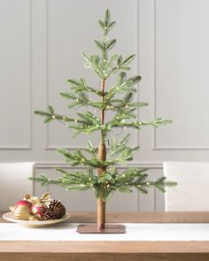 a small christmas tree sitting on top of a wooden table next to a plate with an ornament