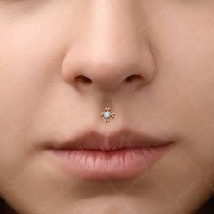 a woman's nose with a tiny blue opal piercing on top of her nose