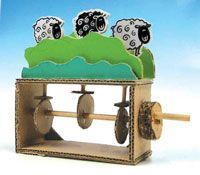 a clock with four sheep on top of it and two wheels attached to the front