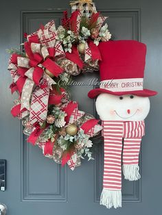 a red and white christmas wreath with a snowman decoration on it's front door