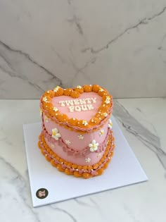 a three tiered cake decorated with orange and pink icing on top of a white table