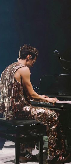 a man sitting at a piano in front of a microphone and wearing gold sequins