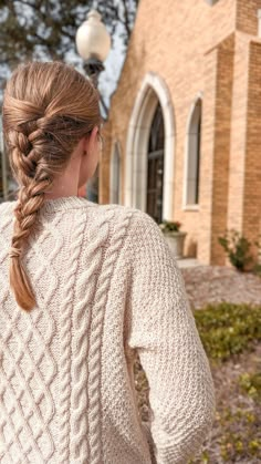 a woman with braids in her hair wearing a sweater