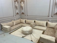 a large sectional couch sitting on top of a white floor next to a round ottoman