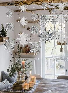 a dining room table with candles and snowflakes hanging from the ceiling