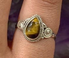 This listing is for a single 925 Teardrop Swirl Tigers Eye Sterling Silver Ring.  A few options are pictured to show the natural variation in the stone.  Tiger's Eye is an opaque stone that has a honey yellow to red brown hue. It is typically seen with bands of a silky luster running parallel through the stone. This stone was found in the early 1800's in South Africa. Tiger's Eye is named because of the similarity to the eye of a tiger. Tiger's Eye helps you understand your own needs, especially in relation to others. Due to its appearance, it is thought to be all seeing. It has been used to focus the mind, making decisions unclouded by emotions, therefore, Tiger's Eye represents Clear Thinking and Understanding. Solar Chakra: The Solar Plexus Chakra brings energy and confidence to everyda Solar Chakra, Tigers Eye Ring, Honey Yellow, Making Decisions, Clear Thinking, Solar Plexus Chakra, Eye Ring, Stackable Ring, Tigers Eye