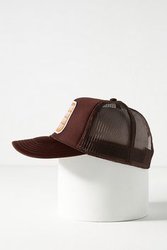 a brown and white trucker hat sitting on top of a white head stand against a white background