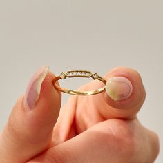 a woman's hand holding a gold ring with diamonds