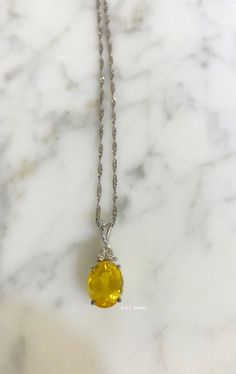 Metal: 14kt White Gold Stone: Yellow Sapphire And Diamond Stone Shapes: Round And Oval-Shape Yellow Sapphire Weight: 3.27 ctw, 9.84 x 7.82 mm Diamond Weight: .08 ctw, round diamonds Measurements Of Pendant From Bail To Bottom Of Pendant: 19.93 mm Weight of entire piece with chain: 2.50 grams Type of Chain: 1.2mm Diamond-cut Singapore Chain Length of Chain: 16 Inches Type of Lock: Spring Ring Note: Other chain styles and lengths available. Pendant can also be sold without chain. Please inquire if Gold Oval Gemstones With Brilliant Cut, Formal Oval Necklace With Accent Stones, Fine Yellow Oval Jewelry, Elegant Yellow Oval Gemstones, Luxury Yellow Oval Necklaces, Elegant Oval Yellow Gemstones, Fine Jewelry Oval Yellow Jewelry, Fine Jewelry Yellow Oval Jewelry, Oval Necklace With Accent Stones