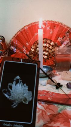 a table topped with a red fan next to a candle