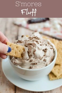 a hand holding a cracker over a bowl of s'mores fluff