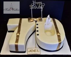 a white cake with gold trimmings and two pieces of luggage on the top