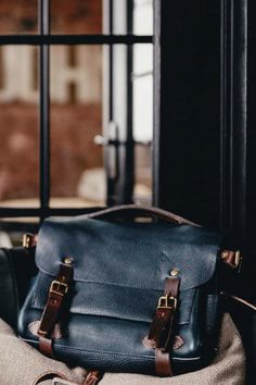 a blue leather bag sitting on top of a piece of cloth next to a window