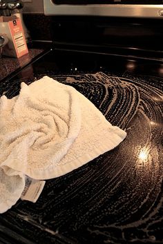 a white towel sitting on top of a black stove top oven burner with a microwave in the background