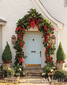 a white house with a blue front door and red ribbon on it's wreath