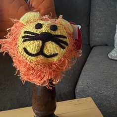 a knitted lion head sitting on top of a wooden stand