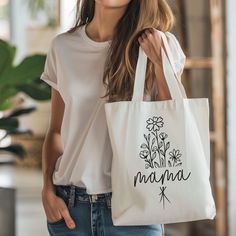 a woman holding a white bag with the word mama printed on it in black ink