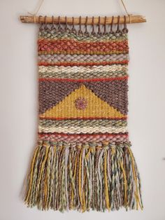 the wall hanging is made out of yarn and has a yellow triangle on it's side