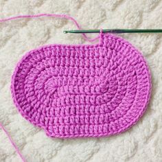 a crocheted pot holder with yarn and scissors next to it on a white surface