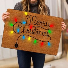 a woman holding up a sign that says merry christmas with colorful lights on the front