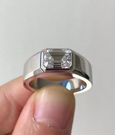 a person holding a ring with a diamond in it's center and two diamonds on the side