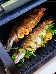 two fish are being cooked on the grill