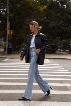 a woman walking across a cross walk in the street