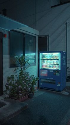 a vending machine sitting in front of a building with flowers growing out of it