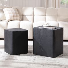 two black square tables sitting on top of a rug in front of a white couch