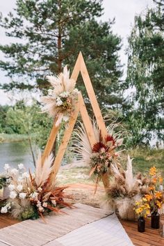 an outdoor ceremony setup with pamodia, feathers and flowers on the table in front of water