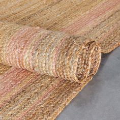 the rug is made out of jute and has pink, beige, and tan stripes