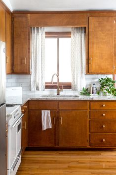 a kitchen with wooden cabinets, white appliances and a window over the sink is shown