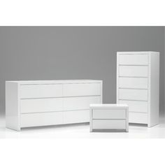 two white dressers and a table against a gray wall