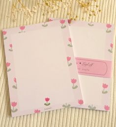 two pink notebooks sitting on top of a table next to each other with flowers