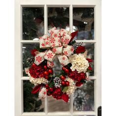 a christmas wreath on a window sill with red and white flowers in front of it