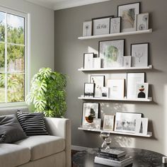 a living room filled with furniture and framed pictures on the wall next to a window