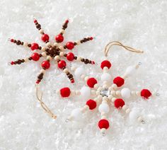 an ornament made out of beads and wooden beads on snow with red and white balls