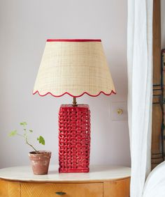 a red lamp sitting on top of a wooden table next to a potted plant