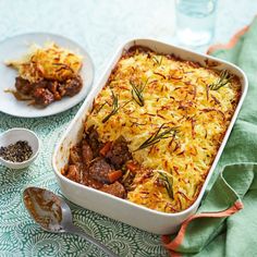 a casserole dish with meat and vegetables in it on a green tablecloth