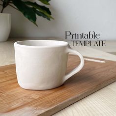 a white cup sitting on top of a wooden cutting board next to a potted plant