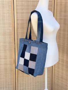 Carry your belongings in style with our medium-sized patchwork tote. This tote features a unique, one-of-a-kind design made from recycled denim and adorned with a vintage button on the exterior to add a touch of elegance. With its versatile use and eye-catching patchwork pattern, this tote is a must-have accessory for the fashion-forward individual. Add a touch of personality to your outfit and make a statement with our patchwork tote - get yours today! Measures 12"H x 14"W x 4"D Everyday Rectangular Recycled Denim Bag, Everyday Recycled Denim Rectangular Bag, Everyday Recycled Denim Rectangular Shoulder Bag, Retro Patchwork Bags For Everyday Use, Daily Use Rectangular Recycled Denim Shoulder Bag, Denim Patchwork Tote Bag, Denim Blue Patchwork Bag For Everyday Use, Daily Recycled Denim Rectangular Shoulder Bag, Denim Patchwork Shoulder Bag For Everyday Use