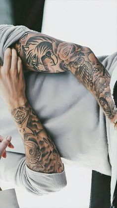 a man with tattoos on his arm holding onto another person's shoulder and hand