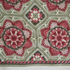 a crocheted tablecloth with red and white flowers on it's edges