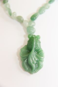 Hand carved big green glass Koi fish pendant dangling from small green Aventurine/jade nuggets necklace. 16" Whimsical Hand-Carved Glass Green Koi Fish Pendant: The Asian Koi fish is very spiritual and very lucky in all aspects of your life. Koi fish is the Chinese symbol of good luck, prosperity, & Tranquility. According to Feng Shui, a fish represents wealth and prosperity because the actual word in Chinese for fish, in Pinyin: yú, 魚, also translates to “abundance” The color green associated with the heart chakra is Green. Green symbolizes harmony, creativity, health, abundance and nature. Green Aventurine: Aventurine meaning comes from the Italian word Aventura which means chance, a hint at the great fortune this stone can bestow upon you. Aventurine is a stone of prosperity. It reinfor Green Jade Spiritual Jewelry, Green Jade Jewelry For Meditation, Green Gemstone Necklace For Good Luck, Spiritual Green Jade Necklace, Green Jade Spiritual Necklace, Green Jade Amulet Necklace, Traditional Green Agate Necklace, Handmade Jade Necklaces For Good Luck, Unique Green Necklace With 108 Beads