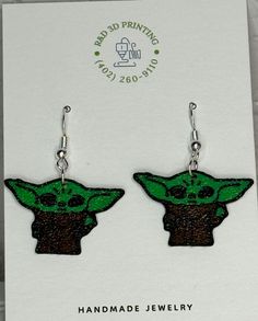 "Embrace the cuteness with our Grogu Earrings! These earrings are 3D printed, making them a unique addition to your jewelry collection. Perfect for any Star Wars fan, they'll add a touch of fun and whimsy to any outfit. May the fashion force be with you!" Themed Dangle Earrings, Handmade Novelty Plug Earrings For Gift, Themed Dangle Pierced Earrings, Themed Pierced Earrings As A Gift, Green Novelty Jewelry For Birthday, Themed Earrings For Pierced Ears As Gift, Themed Gift Earrings, Green Fun Earrings For Gift, Green Fun Earrings For Gifts