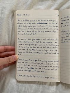 a hand holding an open notebook with writing on it