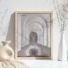 a white vase sitting on top of a table next to a framed photo with an image of a woman