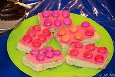 four pieces of cake on a green plate with pink frosting and candy candies