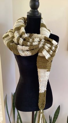 a crocheted scarf on a mannequin with green plants in the background