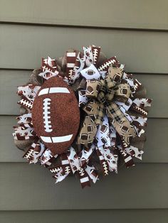 a football wreath is hung on the side of a house with burlocks and bows